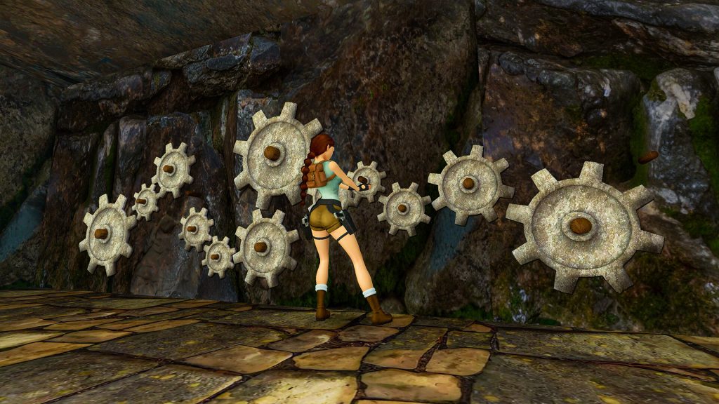 Tomb raider image showing Lara Croft in front of several connected cogs on a rocky wall