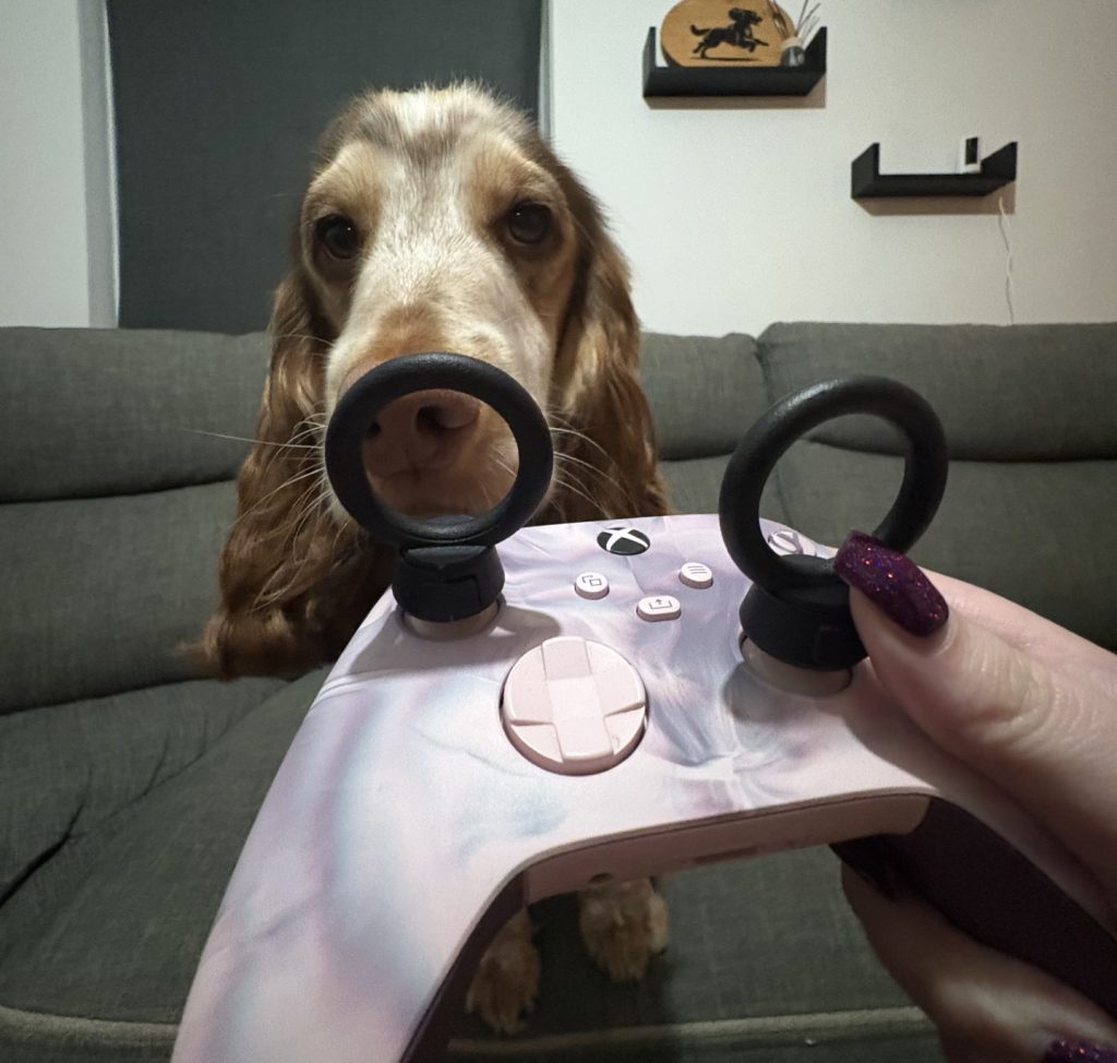 A gaming controller with added attachments for improved accessibility, provided by Thumb Soldiers. Behind is a cute dog.